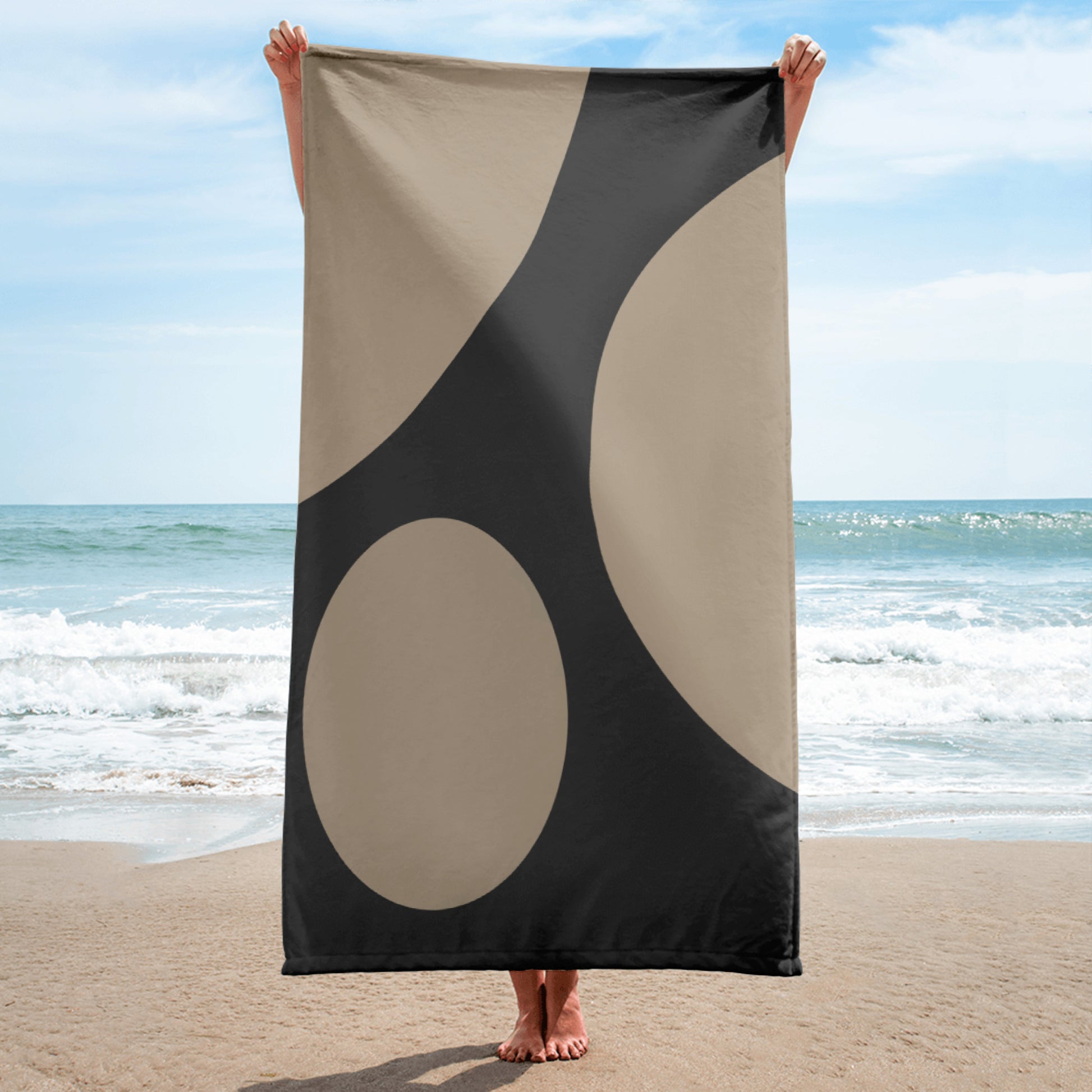 beach and bath towel with beige geometric shapes, displayed by the ocean